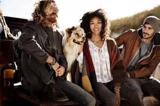 three friends and a dog sitting togehter on the loading space of a pickup