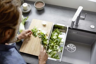 a man cutting vegetables close to the sink