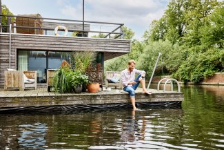 man with laptop chilling on the terrace of his houseboat