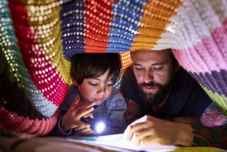 father and son with torch under a blanket