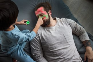 son in painting with fingercolors into his fathers face