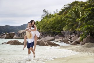 husband has putting his wife piggyback at the beach
