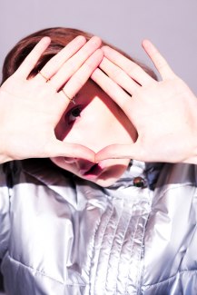 girl with silver snowjacket forming heart with her hands