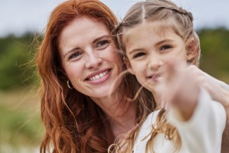 mother and daughter, face to face, looking and pointing into camera