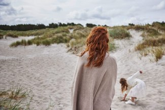 mother is watching daughter playing in the sand