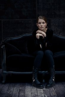 a girl in black cloths on a black sofa