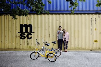 young couple standing in front of yellow container