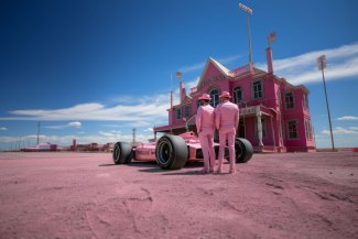 two men with pink suites standing in a kind of western city beside their racingcar