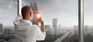 man standing at big window, building a square with his fingers