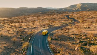 drone shot of a DHL van, driving on a desert road