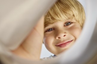young boy looking through a yoghurt cup