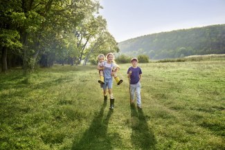 three kids walking over a meadow