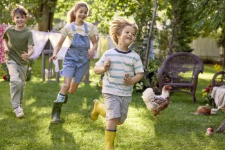 three kids running through a garden