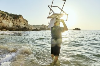 man carrying a folded chair on his head