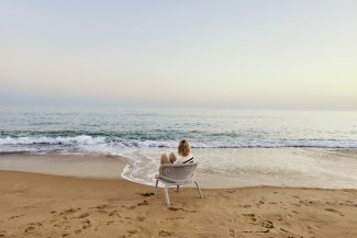 woman is sitting in armchair on a beach