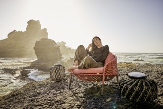 woman in red armchair on cliffs in front of rough sea