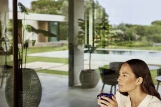 woman holding a cup, huge house in the background