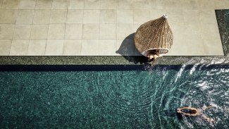 man is swimming in a pool, drone shot