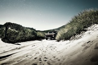 an old pickup driving in the dunes