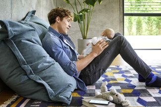 Father with a baby on his lap, sitting on the floor