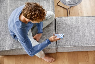 young man holdig a mobile phone to control his smart home