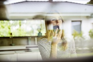 young woman talking in to a smartphone to control his smart home by voice