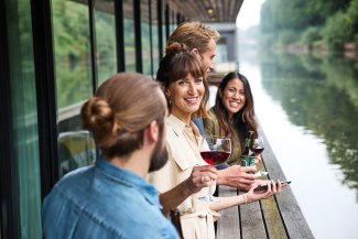 two couples drinking a glas of wine on the terrace of a houseboat