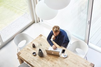 man with tablet computer sitting in kitchen, topshot