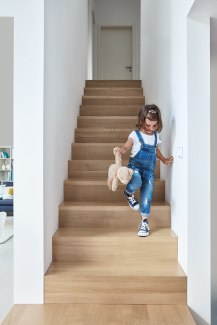 young girl with teddy walking down stairs