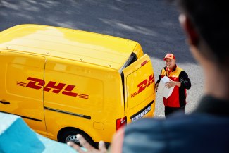 DHL driver standing by his car,  looking up to his customer