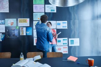 man and woman talking about ideas in front of magnetic pinboard