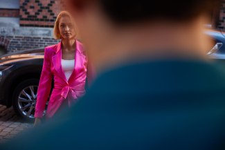 girl with a pink suit in front of her car