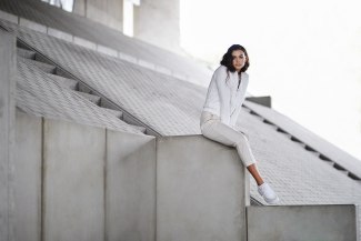 young woman sitting on concrete wall