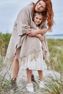 mother covers her daughter with her woolen poncho