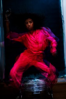 girl with a red jumpsuit dancing above a fan