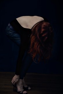 young woman with red hair fixing her shoes, 