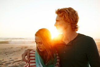 couple close together on the beach during sunset