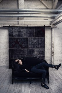 a girl in black cloths on a black sofa