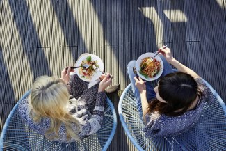 two young women sitting together while enjoying their food