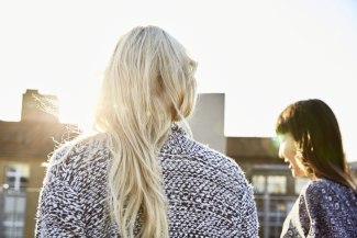 young woman from behind, walking to sunset on roftop