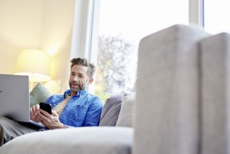 man sitting on sofa, looking on laptop screen man sitting on sofa, looking on laptop screen