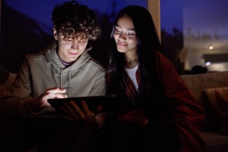 teenager and girlfriend looking into ipad at nighttime teenager and girlfriend looking into ipad at nighttime