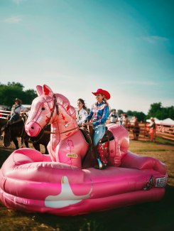 young woman is riding on pink inflatable horse young woman is riding on pink inflatable horse