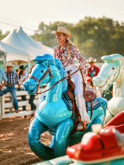 young woman is riding on yellow inflatable horse young woman is riding on blue inflatable horse