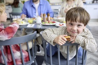 young boy at breakfast table, looking intro camera