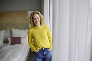 blonde woman standing beside the window, looking into camera