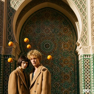 a couple with camelhair cloths standing together while organes flying around their heads